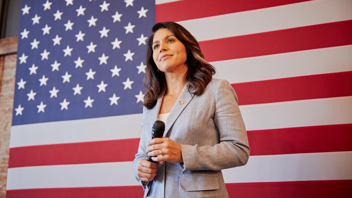 A photo of Tulsi in front of the American flag