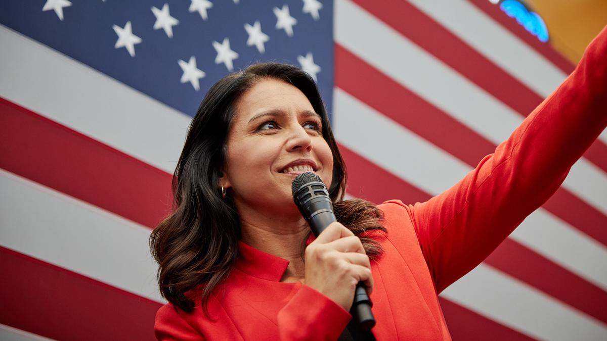 A photo of Tulsi Gabbard in front of the American Flag